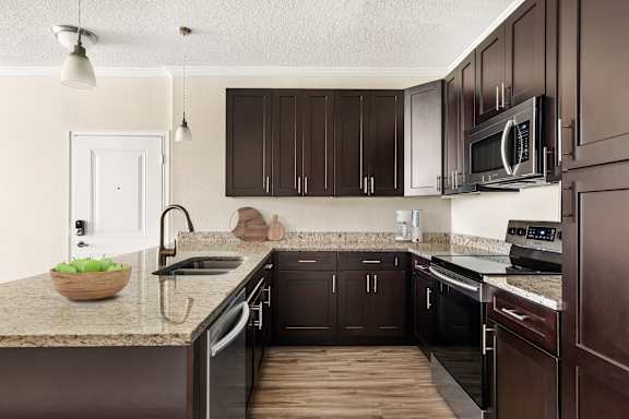 A kitchen with dark brown cabinets and a granite countertop.