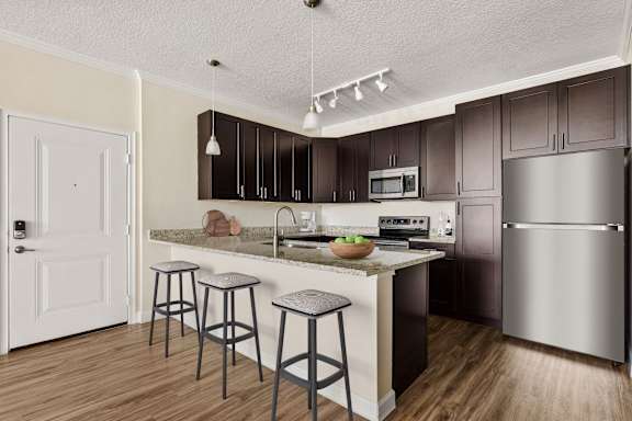 A kitchen with a white door and a counter with a bowl of fruit on it.