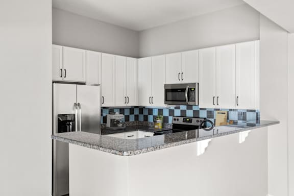 A kitchen with white cabinets and a checkered backsplash.