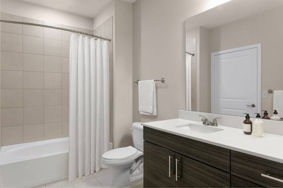 A white bathroom with a toilet, sink, and shower.