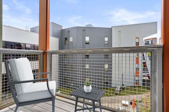 A balcony with a chair and table overlooking a building.