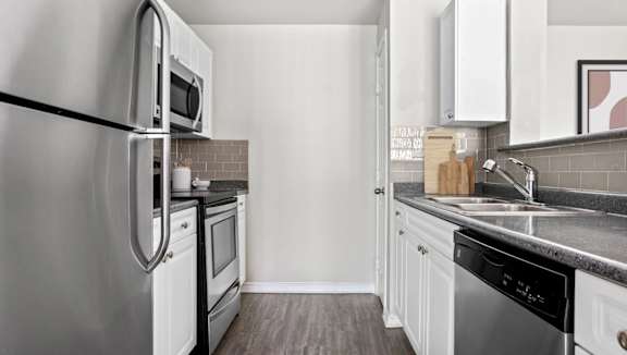 A modern kitchen with a stainless steel refrigerator and white cabinets.