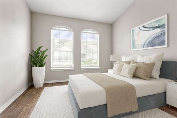 A bedroom with a large bed and a potted plant.