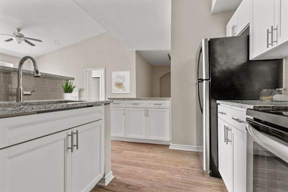 A kitchen with white cabinets and a black refrigerator.