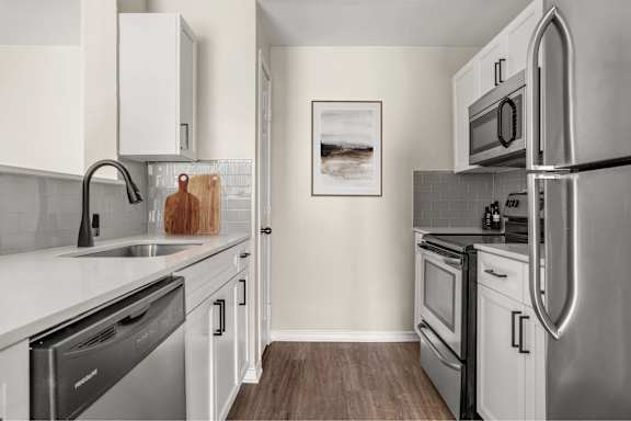 A modern kitchen with stainless steel appliances and white cabinets.