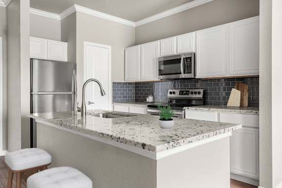 A kitchen with a marble countertop and white cabinets.
