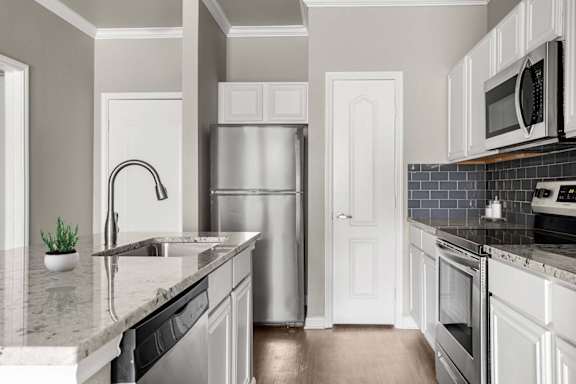 A kitchen with a refrigerator, sink, and oven.