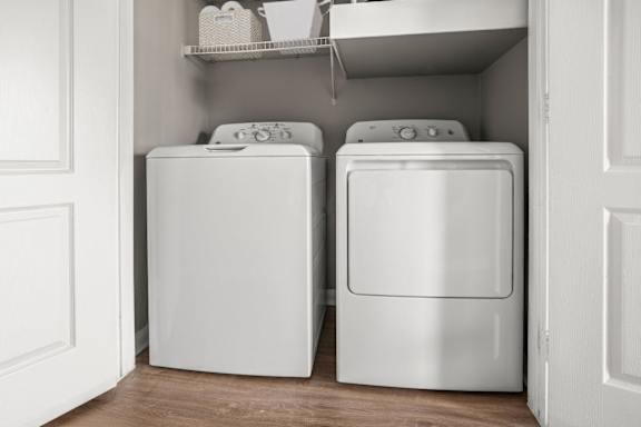 Two white washing machines in a laundry room.