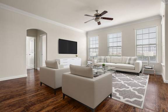 A living room with a white couch and a television on the wall.