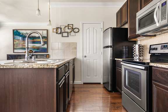 A kitchen with a black refrigerator and stove top oven.
