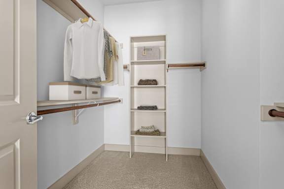 A white closet with a shelf and a white door.