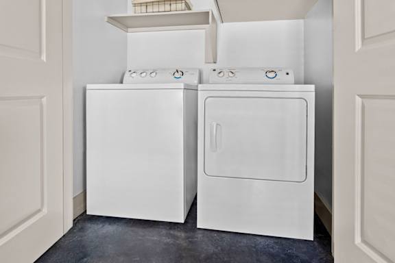 Two white front loading washing machines in a laundry room.