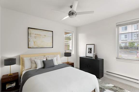 A bedroom with a bed, nightstand, and a painting on the wall.