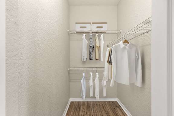 A white closet with clothes hanging on a rack.