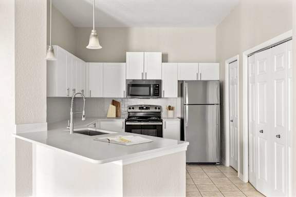 A modern kitchen with white cabinets and appliances.