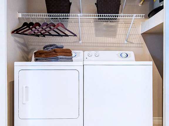 A white dryer is sitting next to a white washing machine.