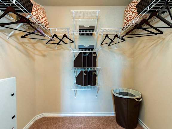 A room with a white closet and a brown trash can.