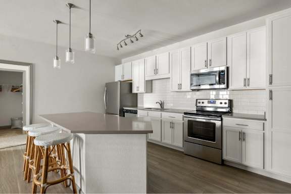 A kitchen with white cabinets and a grey countertop.