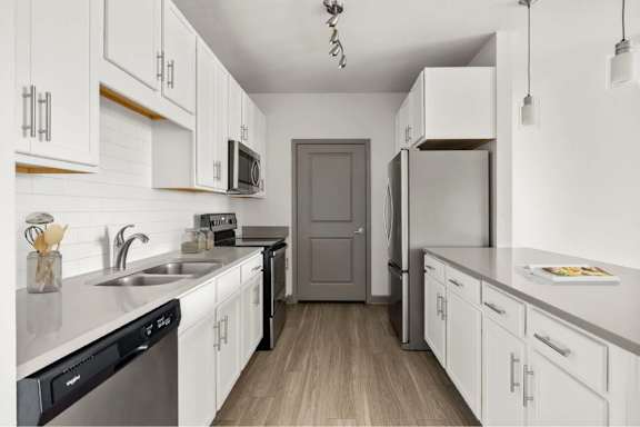 A kitchen with white cabinets and a wooden floor.
