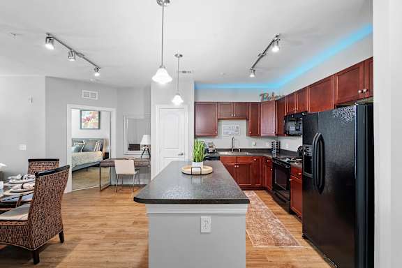 A kitchen with a black refrigerator and wooden cabinets.