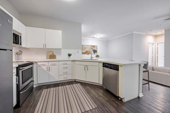 A modern kitchen with white cabinets and a wooden floor.