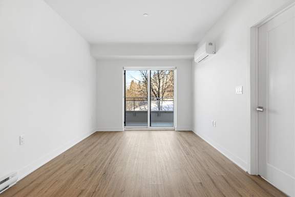 A room with a wooden floor and a window showing a tree outside. at Château golf, Gatineau Quebec