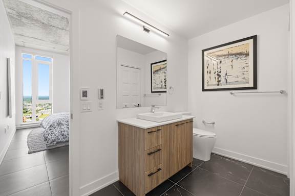A bathroom with a wooden vanity and a painting on the wall.