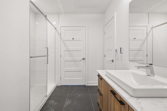 A white bathroom with a sink, mirror, and two doors.