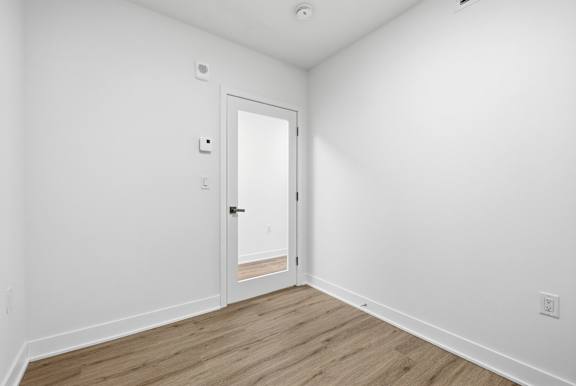 A white door is in a room with wood flooring. at Château golf, Gatineau