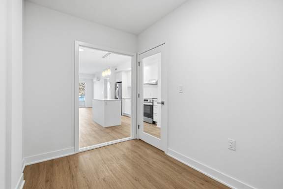A white room with a wooden floor and a doorway leading to another room. at Château golf, Gatineau Quebec