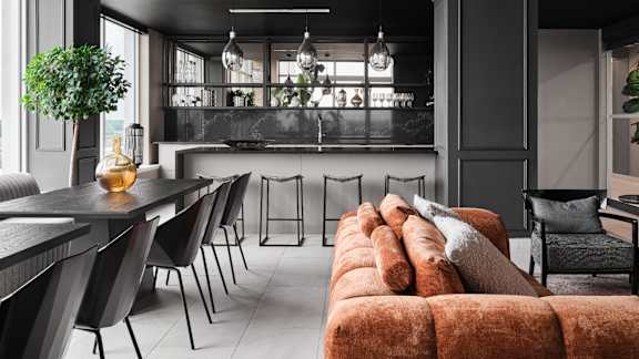 A modern living room with a long couch and a dining table. at Petries Landing I Apartments , Ontario, K4A 1K4