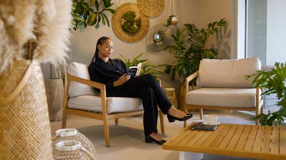 A woman in a black outfit is sitting on a white couch with a tablet in her hands at The Dale Apartments , Ottawa, ON, K1Y 4Y5