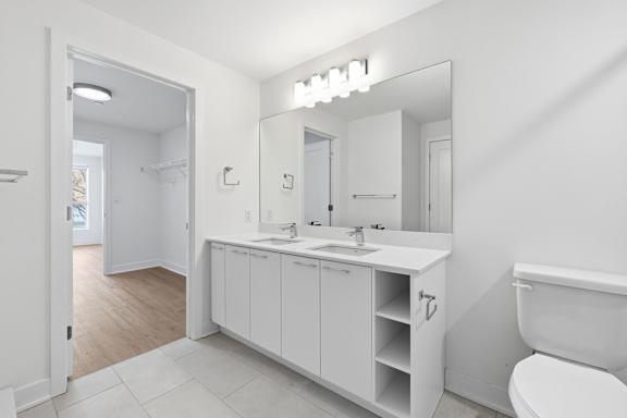 A white bathroom with a sink, mirror, and toilet. at Château golf, Gatineau, QC