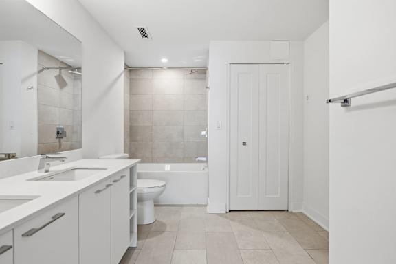 A white bathroom with a tub, toilet, and sink. at Château golf, Gatineau, QC J9H 0M9