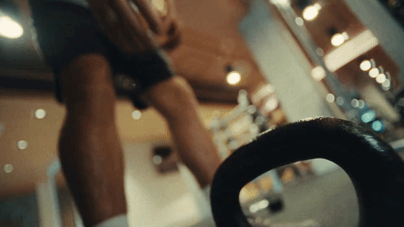 A man is lifting a barbell in a gym.