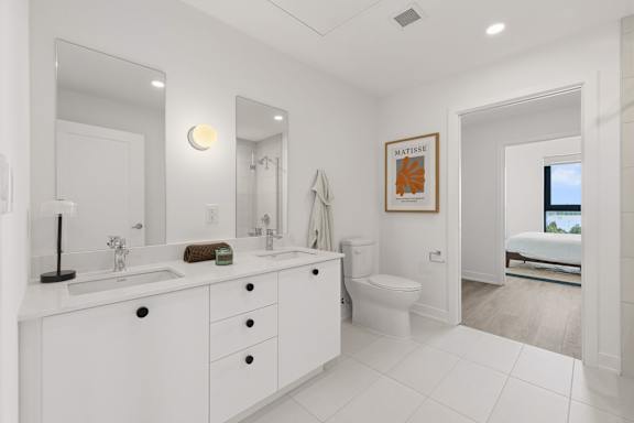 A white bathroom with a large mirror and a white toilet.