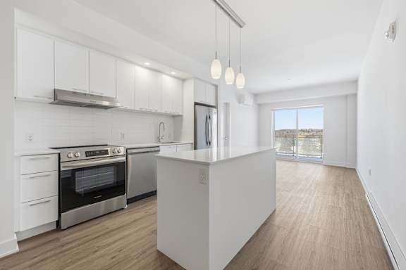 A modern kitchen with a stainless steel oven and white cabinets. at Château golf, Quebec, J9H 0M9