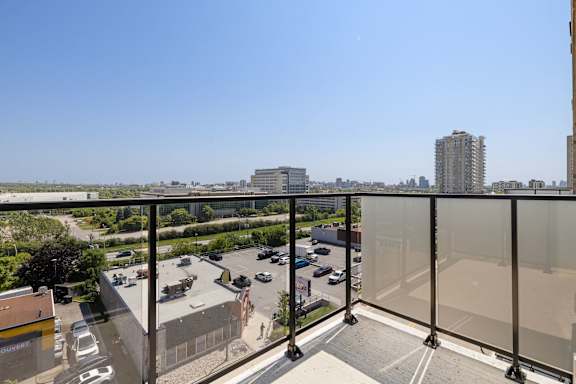 A balcony with a view of a parking lot and buildings.