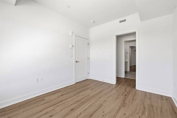 A room with white walls and wooden flooring with two doors. at Château golf, Gatineau, QC J9H 0M9