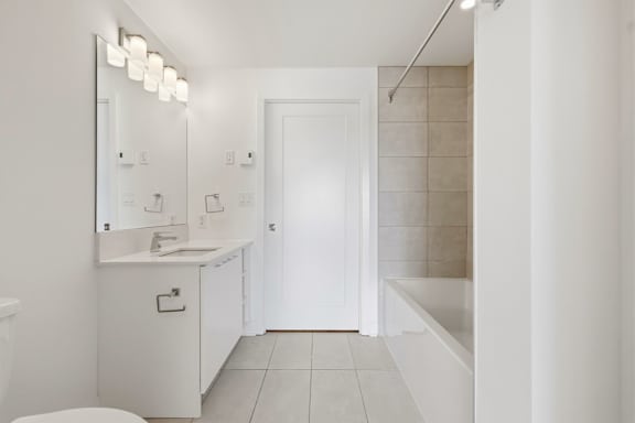 A white bathroom with a toilet, sink, and mirror. at Château golf, Gatineau, QC