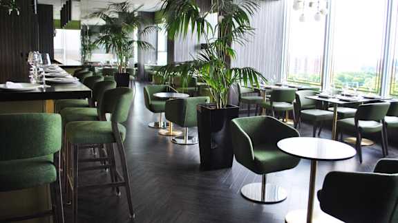 A restaurant with green chairs and tables.