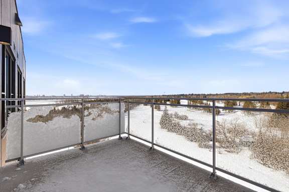 A snow-covered balcony with a metal railing and a building on the left. at Château golf, Gatineau, QC