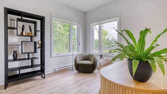 A living room with a round table and a potted plant on it.