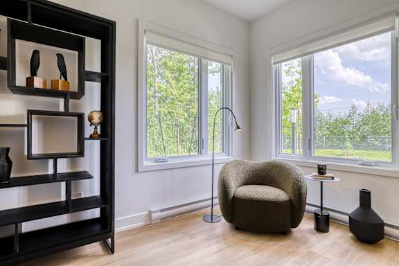 A living room with a chair, a table, and a shelf with vases.