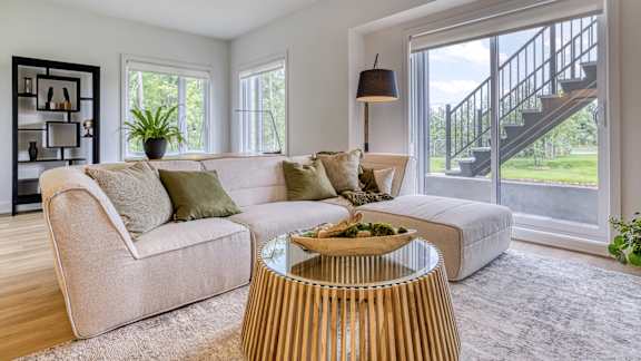 A living room with a beige couch, a wooden coffee table, and a staircase in the background.