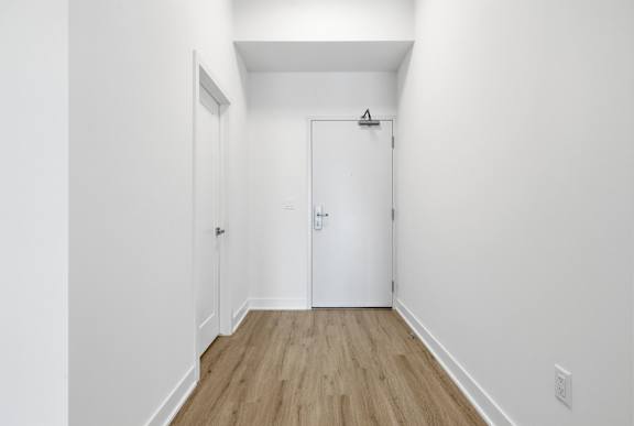 A white door with a black handle is in a white room with a wooden floor. at Château golf, Gatineau, QC