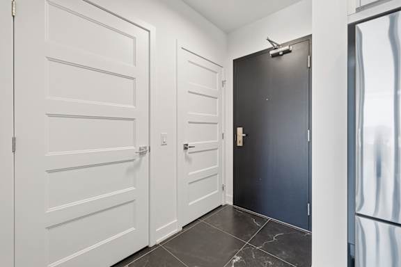 A hallway with a black door and white doors on either side.