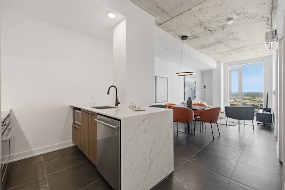 A modern kitchen with a marble countertop and stainless steel appliances.