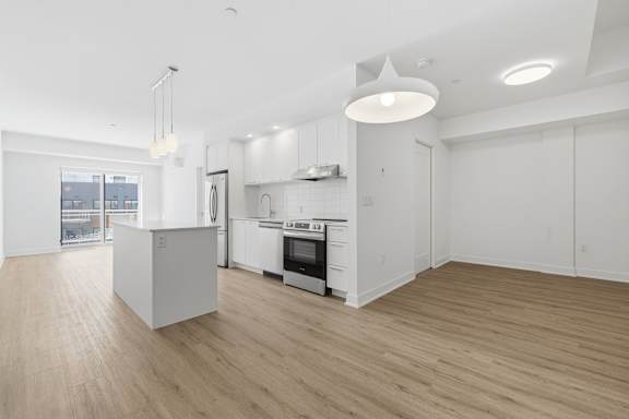 A modern kitchen with white cabinets and a wooden floor. at Château golf, Gatineau, J9H 0M9