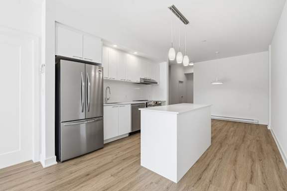 A kitchen with a refrigerator, sink, and wooden floors. at Château golf, Gatineau Quebec